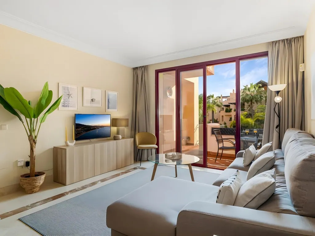 Apartamento Bahía Alcántara Salón moderno con sofá gris, terraza y vistas tropicales