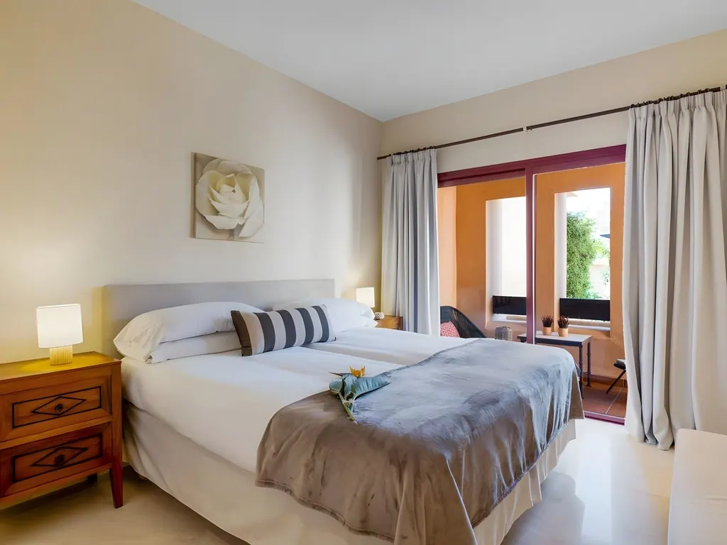 Apartamento Bahía Alcántara Habitación moderna con cama doble, mesitas de noche y puertas al balcón
