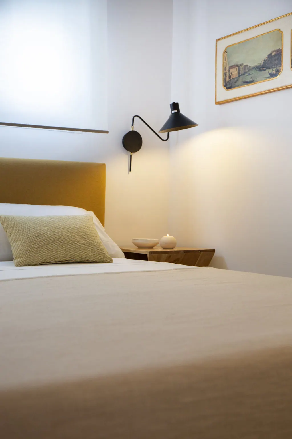 Casa Vacacional Dormitorio minimalista con lámpara de pared negra y cabecero mostaza