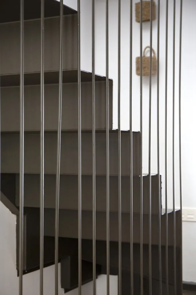 Casa Vacacional Escalera moderna con barandilla metálica vertical y estantería integrada oscura
