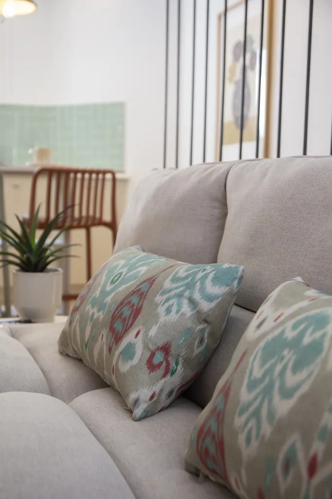 Casa Vacacional Sofá gris moderno con cojines decorativos estampados en salón luminoso