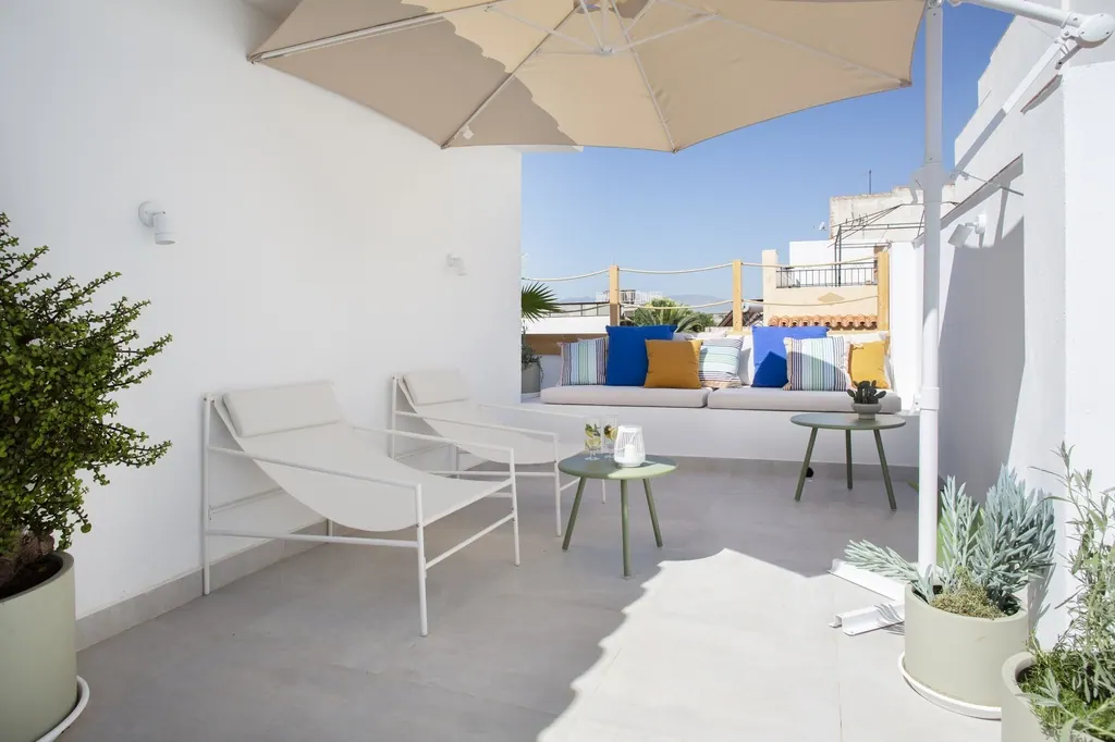 Casa Vacacional Terraza moderna minimalista con muebles blancos y sombrilla beige