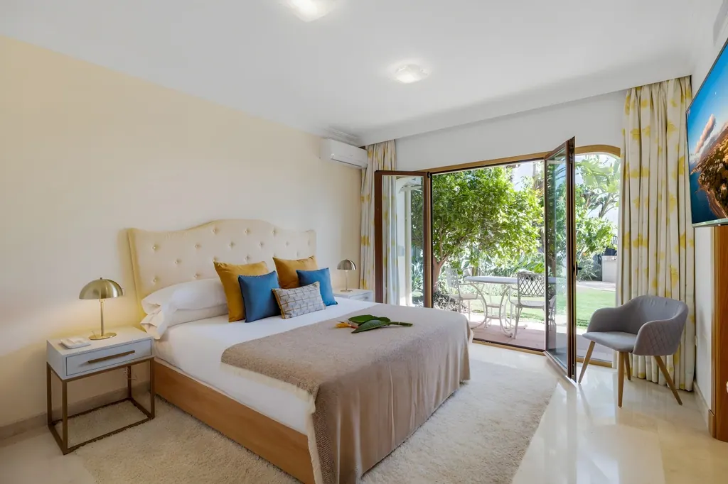 Villa los Arqueros Golf Habitación moderna con cama tapizada y puertas abiertas al jardín
