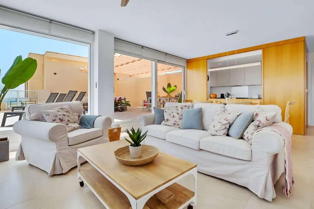 Ático en la Carihuela Sala de estar moderna con sofás blancos y cocina integrada vista al exterior