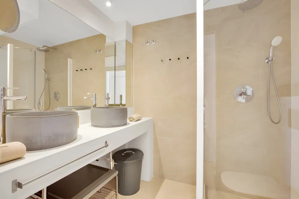 Ático en la Carihuela Baño moderno con lavabos de hormigón, ducha y acabados beige minimalistas
