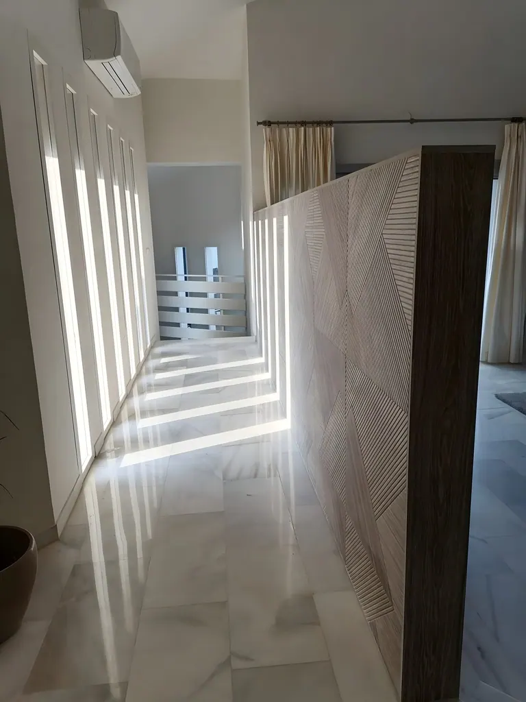 Chalet Unifamiliar Pasillo moderno con luz natural filtrada por ventanas verticales y puertas decorativas
