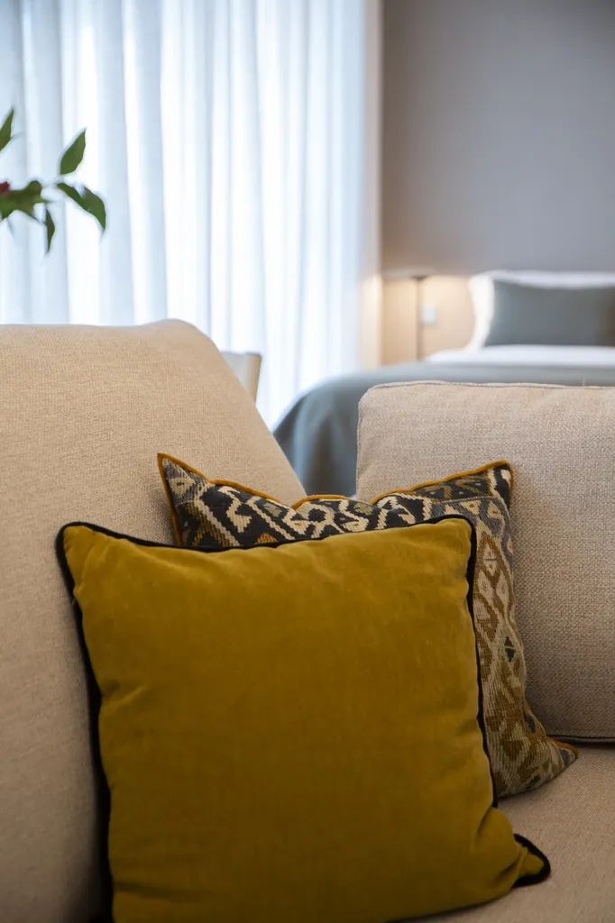 Málaga Towers Cojines decorativos amarillo mostaza y estampado en sofá beige moderno