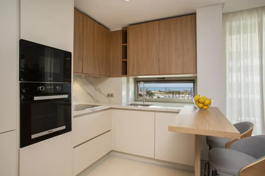 Málaga Towers Cocina moderna con muebles de madera y encimera blanca minimalista