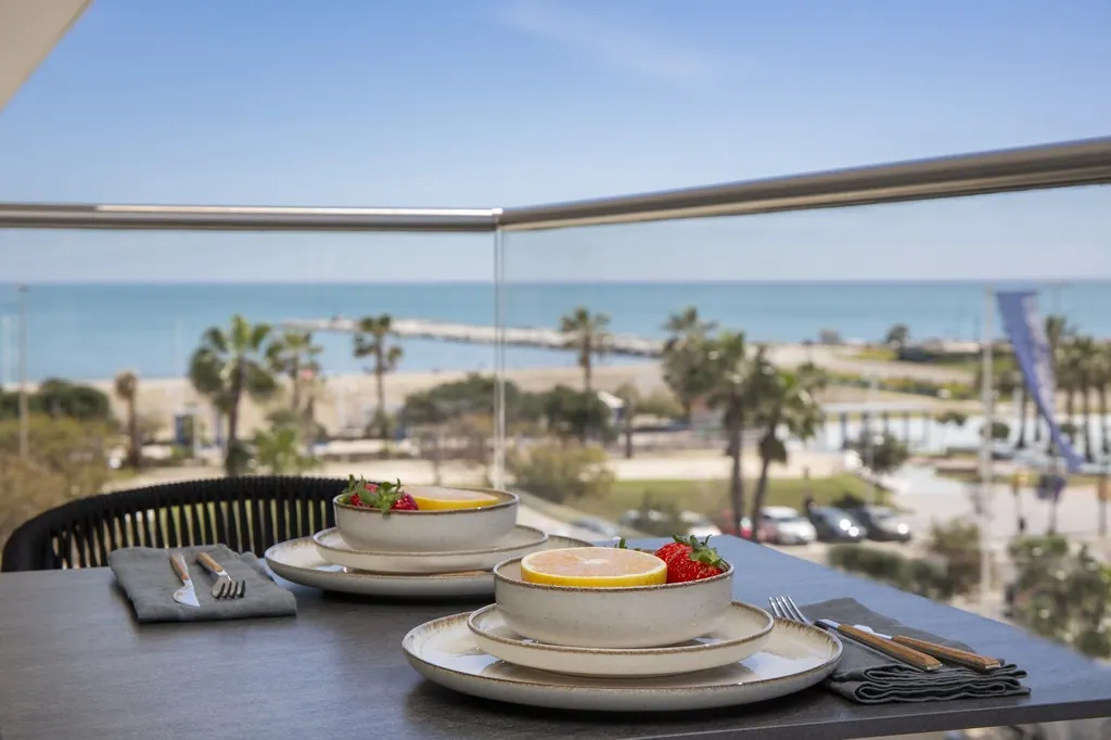 Málaga Towers Mesa con postres y vista al mar mediterráneo con palmeras