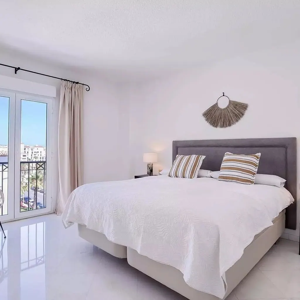 Las Gaviotas Dormitorio moderno blanco con cama gris y balcón con vistas