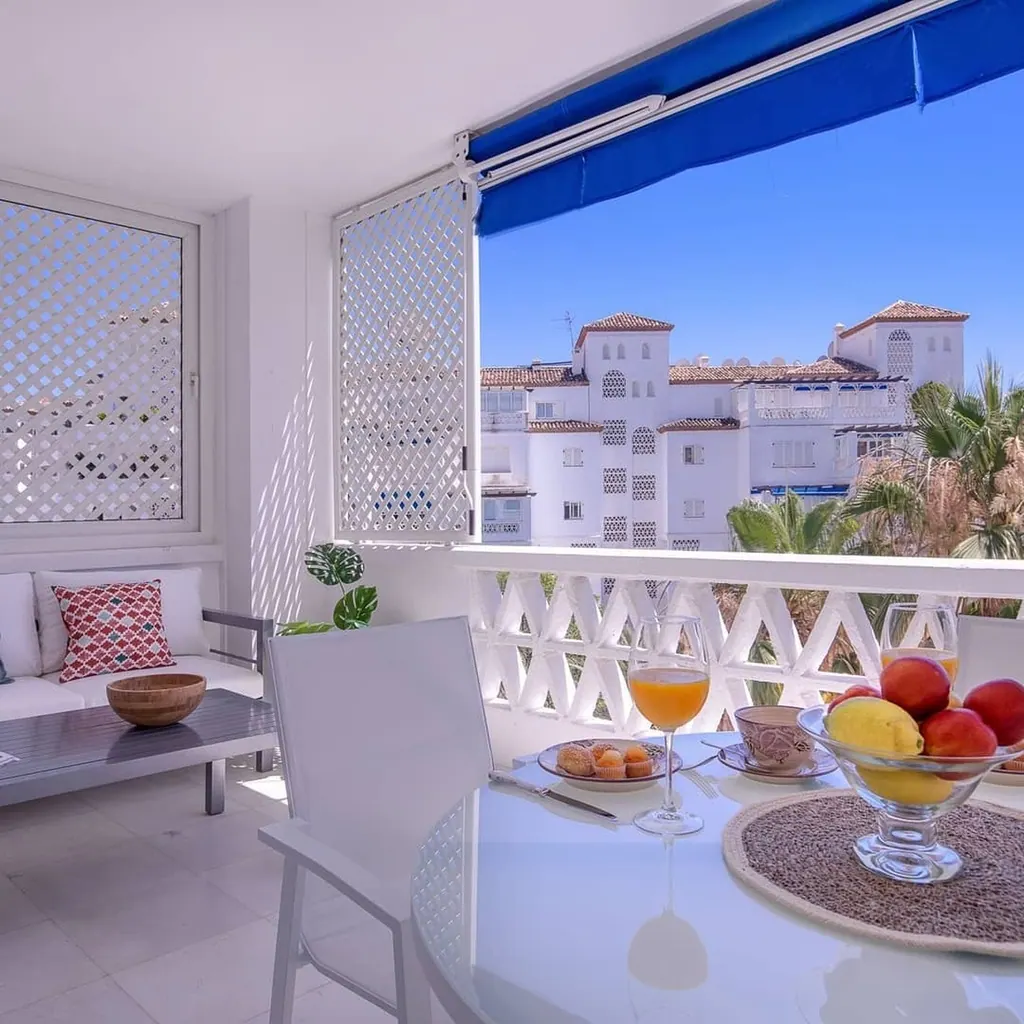 Las Gaviotas Terraza moderna con desayuno y vistas a edificios blancos mediterráneos