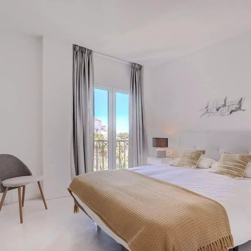Las Gaviotas Dormitorio minimalista blanco con detalles en beige y decoración natural mediterránea