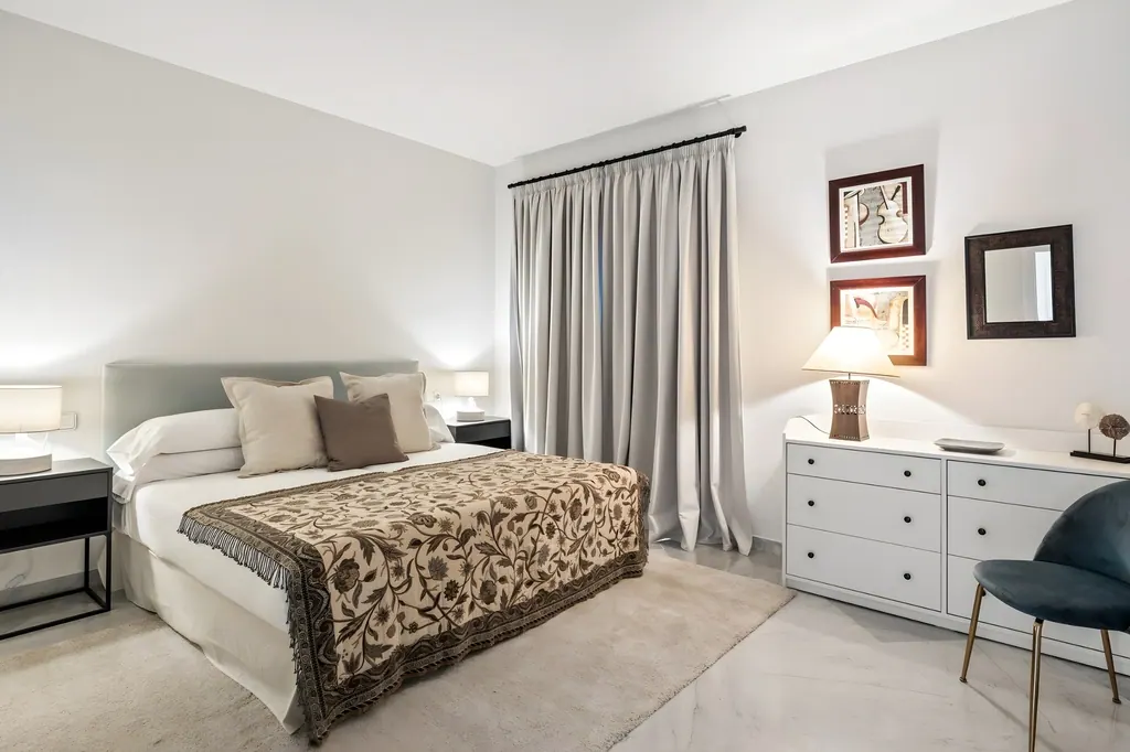 Casa Sevilla Dormitorio moderno con cama blanca, cortinas grises y cómoda blanca