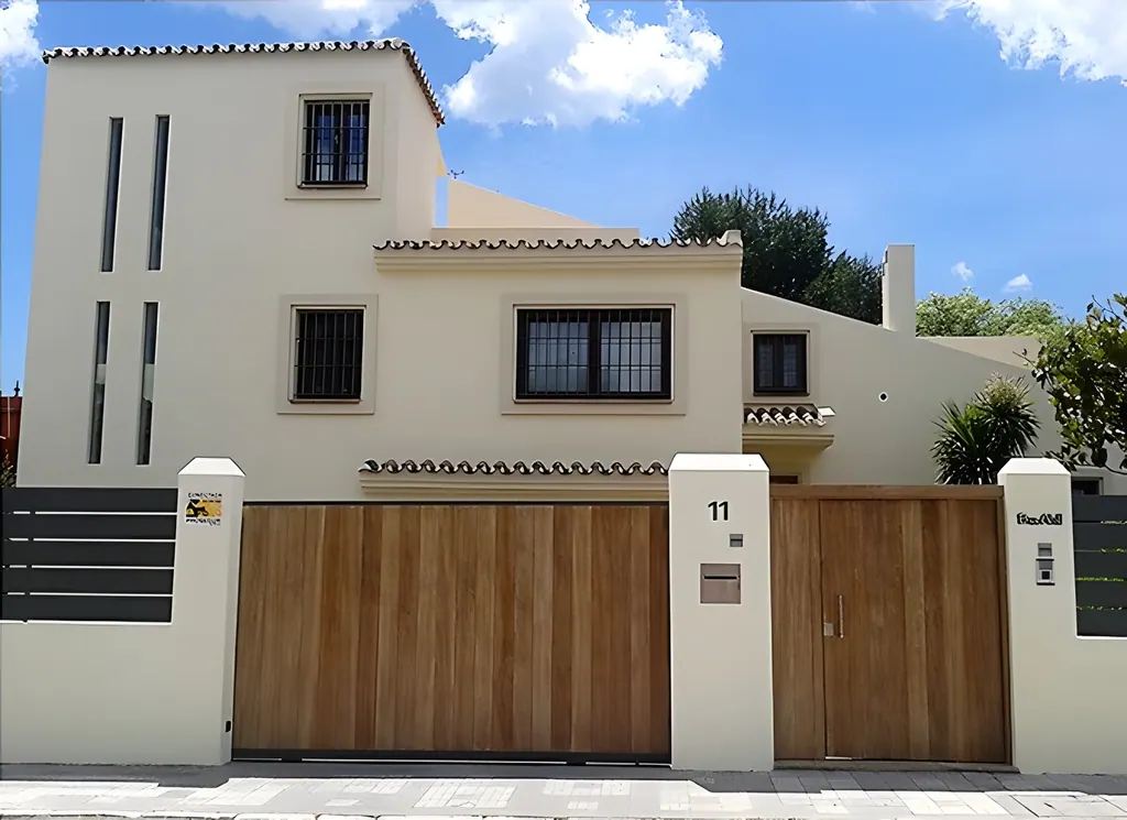 Villa el Olivar Fachada de villa moderna con portón de madera y número 11