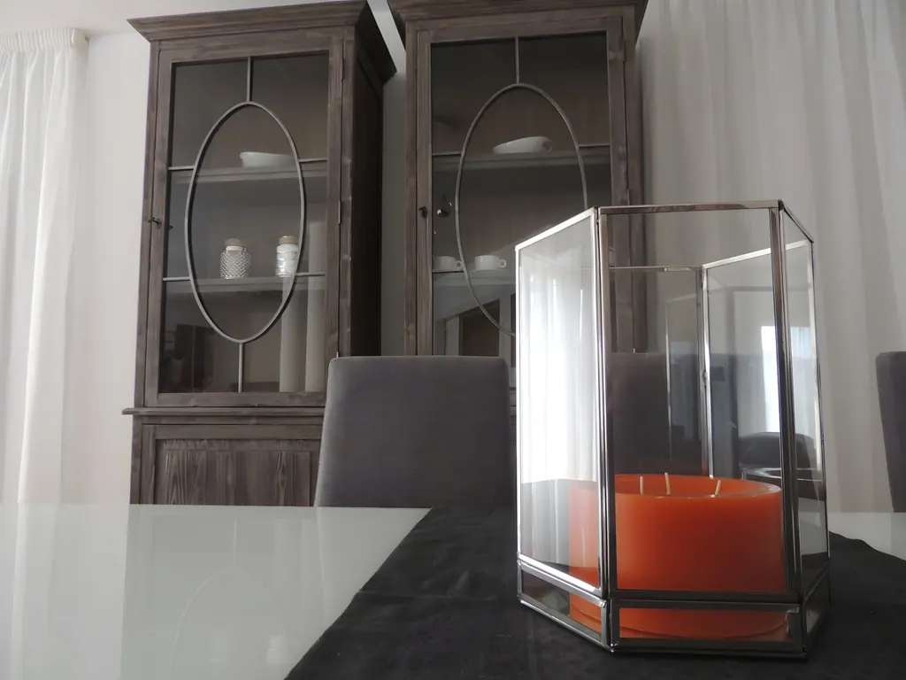 Villa Nueva Andalucía Vela naranja decorativa en farol de vidrio sobre mesa de comedor moderna